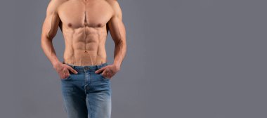 Formda, kaslı gövdesi ve güçlü kol pazısı olan gömleksiz bir adam. Kotla, sporla, triseps kaslarıyla poz veriyor. Seksi çıplak gövde, fotokopi alanı olan pankart