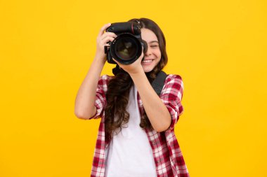 Ergen yaşam tarzı, genç hippiler profesyonel kamera taşıyor. Fotoğraf makinesi olan bir kız, stüdyo arka planında izole edilmiş. Mutlu ergen, pozitif ve gülümseyen genç kız duyguları