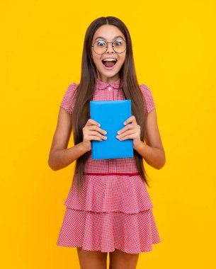 Şaşırmış genç kız. Kitaplarla izole edilmiş stüdyo geçmişi olan liseli bir kız. Heyecanlı bir ifade, neşeli ve mutlu.