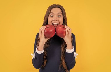 Sarı arka planda kırmızı vitamin elmasını ısıran mutlu çocuk, diş bakımı..
