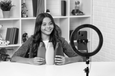 Şampuan şişeli vlogger. Akıllı telefondan video blogu hazırlıyorum. Blog lambası. Saç kremi. Neşeli kız selfie çekti. Çocuk güzellik blogcusu. Gençler için kozmetik ürünü sunan çocuk.