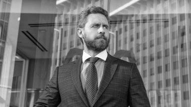 Takım elbiseli başarılı bir adam. Yönetici ofis dışında. Erkek resmi moda. Kendine güvenen sakallı patron. Formalite portresi giymiş olgun bir iş adamı. iş başarısı.