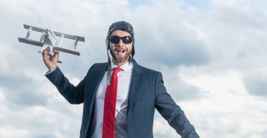 Takım elbiseli mutlu iş adamı ve pilot şapkalı uçak oyuncağı..