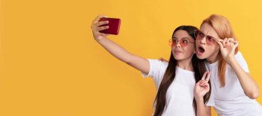 Anne ve kız çocuk afişi, kopyalama alanı, izole edilmiş arka plan. Neşeli anne ve kızı akıllı telefondan selfie çekiyor, aile selfie 'si.