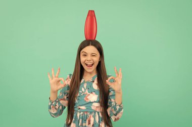 Uzun saçlı mutlu çocuk şampuan şişesini tut. Tamam jest yap, reklam yap..