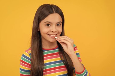 Kız multivitamin yiyor. Sağlıklı bir yaşam tarzı. Çocukluk sağlığı. Gıda takviyesi. Doğal hap ürünleri olan bir kız. Vitamin ürünü sunuyorum. Gülümseyen çocuk hap yiyor. Çocuklar için kapsül biçimli tablet.