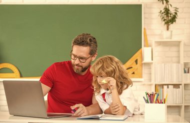 baba ve çocuk sınıfta laptopla, aileyle ders çalışıyor..