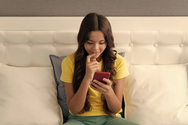 智能手机的一代 快乐的孩子坐在床上用智能手机 用智能手机聊天 手机通讯 用手机聪明点 — 图库照片