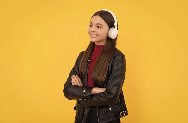 明るい10代の女の子は黄色の背景にヘッドフォンで音楽を聞きます ラーニング — ストック写真