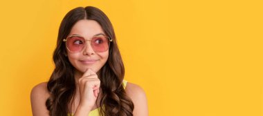 Yaz gözlüklü mutlu hayalperest çocuğun sarı arka planda kıvırcık saçları var. Çocuk yüzü, yatay poster, izole edilmiş genç kız portresi, fotokopi alanı olan pankart