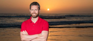 Gün batımında sahilde neşeli bir adam. Sahilde fotokopi, tatil. İnsan yüzü portresi, kopyalama alanı olan pankart