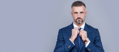 Takım elbiseli başarılı bir iş adamı kravat takıyor, moda yapıyor. İnsan yüzü portresi, kopyalama alanı olan pankart