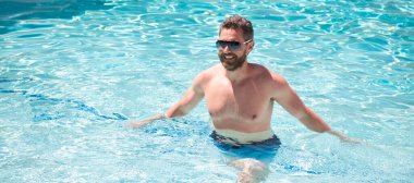 Yaz kaplıcası tatili. Havuzdaki mutlu yakışıklı adam. Havuz partisi. İnsan yüzü portresi, kopyalama alanı olan pankart