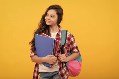 Eğitim ve bilgi. Lisede. Not defteri ve sırt çantası olan bir kız öğrenci. Okula dönüyorum. Genç kız çalışmaya hazır. Mutlu çocukluk. Çocuk ödevlerini kitaplarla yapacak. Gülümseyen sevimli öğrenci.