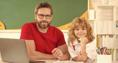 baba ve oğul sınıfta dizüstü bilgisayarla, online eğitimle okuyorlar..