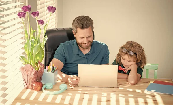 boy do homework with private tutor. webinar video lesson. online education on laptop. homeschooling and elearning. back to school. father and son use communication technology at home. family blog.