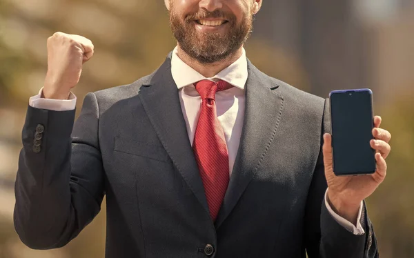 cropped successful businessman presenting product. success. presentation on smartphone. office manager ready for video conference. grizzled man showing phone screen. webinar advertisement.