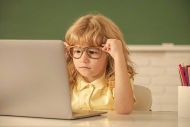 Bilgisayarlı, gözlüklü zeki inek çocuk. Eylül 1 e-öğrenim. Çocuk bilgisayarda çalışıyor. Sınıftaki genç çocuk. Okula dönüyorum. Bilgi günü. çevrimiçi eğitim kavramı.