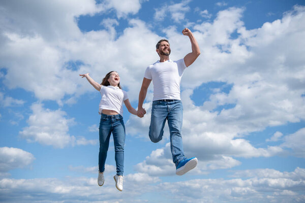 carefree father and daughter jump in sky.