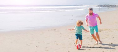 Baba ve oğul plajda futbol ya da futbol oynuyor. Mutlu baba ve oğul yaz kumsalında top ve arkadaşlıkla futbol oynuyorlar..