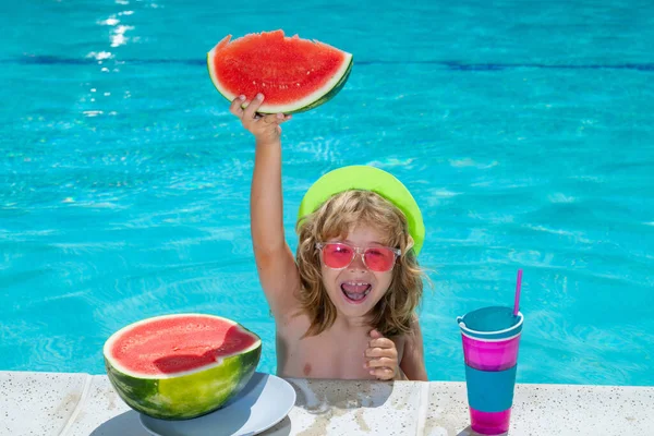 Kid boy playing in swimming pool. Summer vacation concept. Summer kids portrait with watermelon in pool water