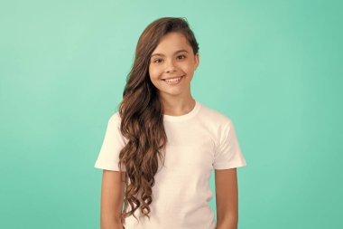 Mavi arka planda beyaz gömlekli, uzun kıvırcık saçlı mutlu çocuk..