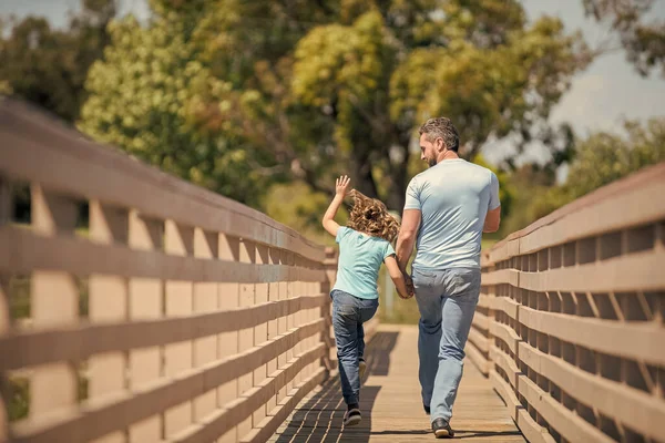 Aile değeri. Çocukluk ve ebeveynlik. Ebeveyn, küçük çocukla rahatlar. Komik bir yaz gününde çocuklu bir baba. Ebeveynlik ve babalık. Babalar günü. Arkadan bak. Mutlu baba ve oğul dışarıda koşuyor..