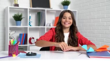 Mutlu çocuk okul masasında origami uçakları uçuruyor..