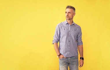 adult man with hand watch on yellow background, copy space, fashion.