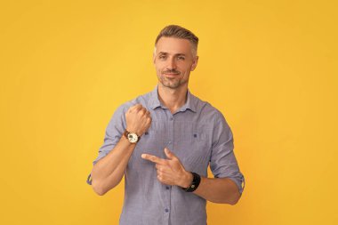 Olgun erkek işaret parmağı sarı arka planda saat, zaman.