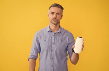 Sarı arka planda saç kremi gösteren adam..