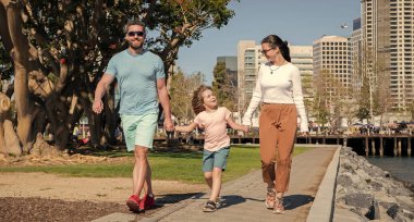 Mutlu genç anne ve baba parkta oğluyla yürüyor..