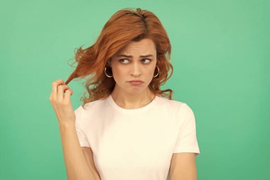 Mavi arka planda kıvırcık saçlı mutsuz kızıl kadın, hayal kırıklığı..