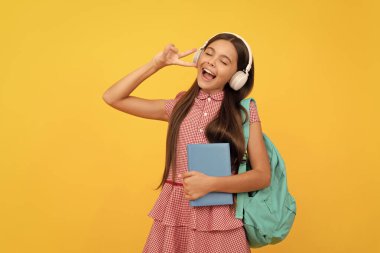 Müzik. Mutlu şarkı söyleyen genç kız sırt çantası taşıyor. Okula dönüyorum. Bilgi günü. Eğitim konsepti. Kulaklık takan ve ders kitabı olan bir çocuk. 1 Eylül. Mutlu çocukluk. Okul çantalı çocuk.