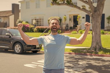 Bağıran adam araba ve evin yanında duruyor..