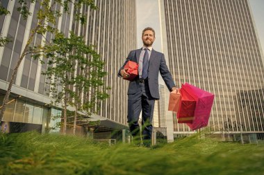 boxing day. handsome man with present box. boss carry birthday gift. guy hold shopping bags. mens day. happy businessman with packages. sale and discount. surprise for her. be my valentine.