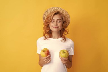 Hasır şapkalı gülümseyen kızıl kadın, elma, organik yemek..