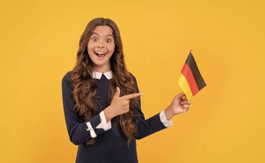 Genç kız futbol hayranı. Yönü seç. Alman bayrağını işaret eden şaşkın çocuk. Schengen ülkesinde turistik vize. Çocuk yurtdışına seyahat edip eğitim görüyor. Almanya tatili. yabancı okulda eğitim.