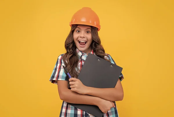 wow. surprised girl in protective hard hat. amazed child in helmet hold project. construction documents. signing a contract. kid education. future engineer hold clipboard. safety work expertise.