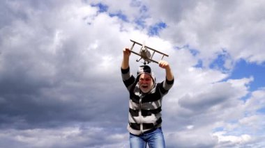 Happy greybeard man pretend flying on wooden airplane in sky, travelling.