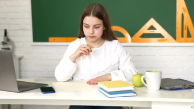 Pensive kid write in copybook doing schoolwork in classroom, lesson.