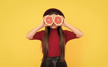 Sarı arka planda greyfurt arkasında gülümseyen çocuk, antioksidan..