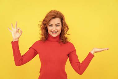 Neşeli kızıl saçlı kadın reklam için ürünü fotokopi alanıyla sunuyor..