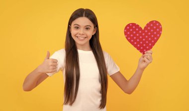 Aşk hediyesi. kopyalama alanı. Aşk hediyesiyle gülümseyen çocuk. Tatlım. Sevgililer günü indirimi. Kalbi olan bir çocuğun portresi. Sevgililer günün kutlu olsun. Sevgilim olur musun? Sarı arka plandaki genç kız..