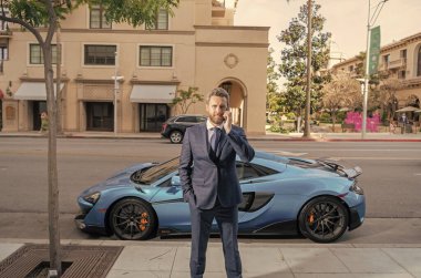 Kendine güvenen bir adam arabada telefon görüşmesi yapar..