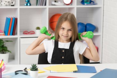 Çocuk okulda spor kemerlerini tutuyor..