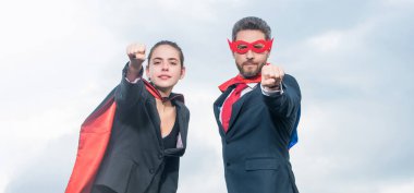 Gökyüzü geçmişinde süper kahraman kıyafeti giyen cesur iş çifti.