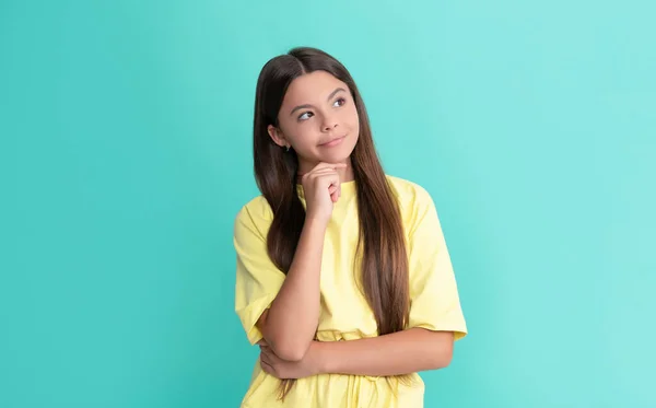 pondering teen girl with long hair on blue background, making decision.
