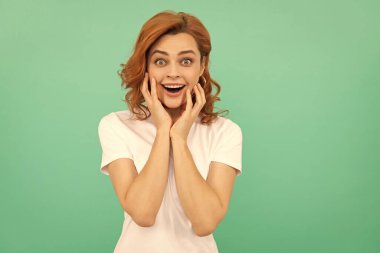 surprised portrait of redhead lady on blue background. express positive emotions. surprise. woman with curly hair. beauty and fashion. female fashion model. pretty look of young girl.
