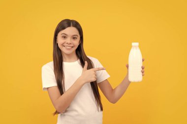 Mutlu çocuk, süt ürünlerini işaret ediyor. Genç kız süt içecek. Sağlıklı bir yaşam tarzı. Çocukluk gıdası. Günde bir içki. Süt ürünleri. Kahvaltıda yoğurt. Çocuk süt şişesini tutuyor..